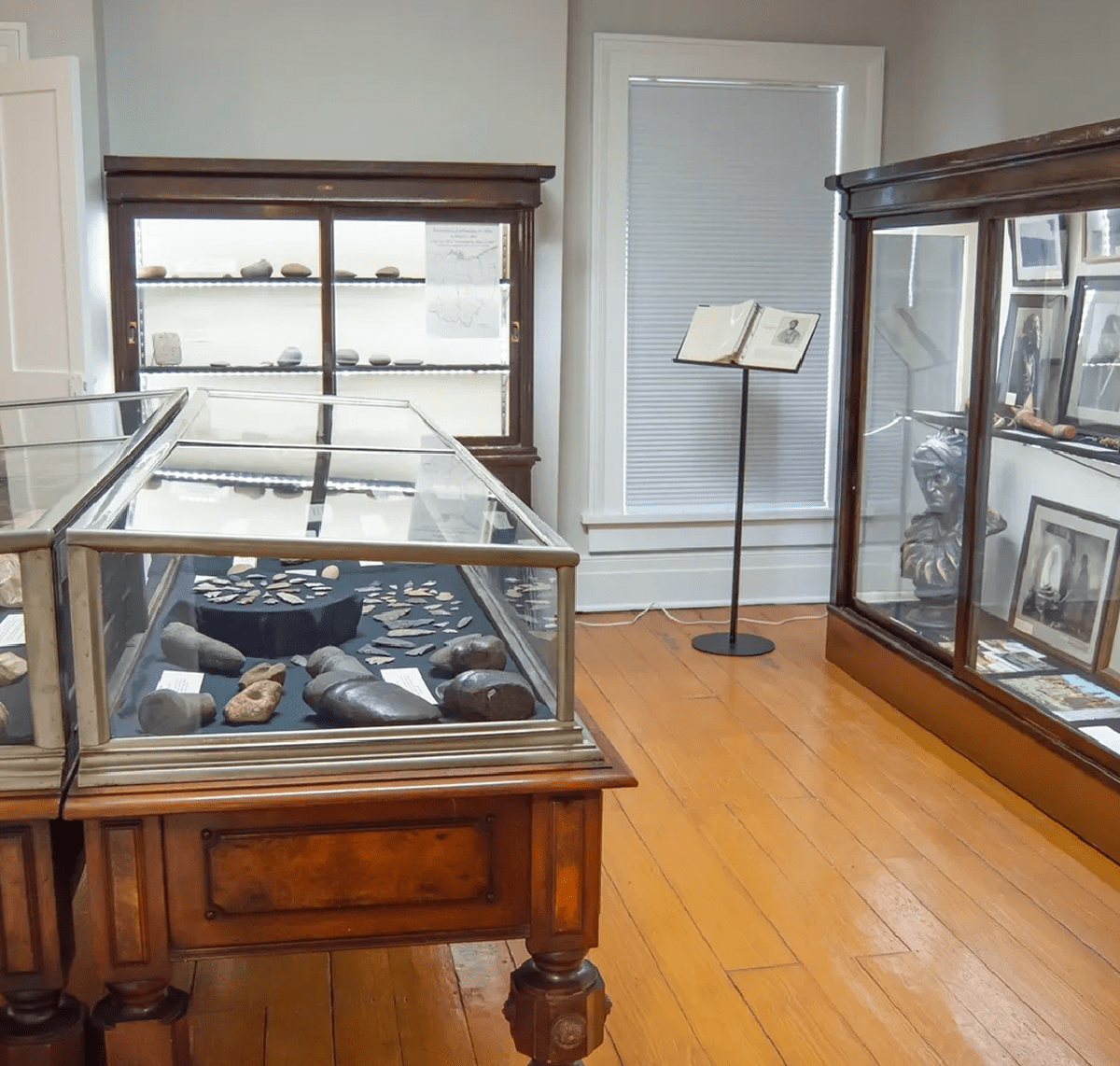 A small museum room with wooden display cases and framed pictures.