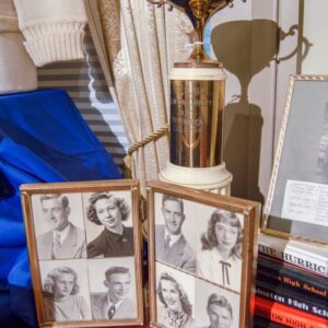 A collection of framed black-and-white celebrity photos on a table with books.