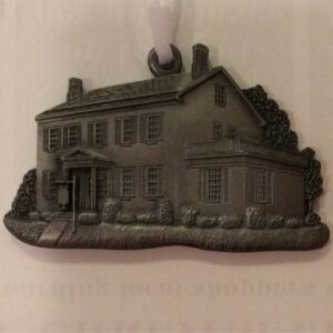 A detailed miniature model of a traditional two-story house with a chimney and landscaping.