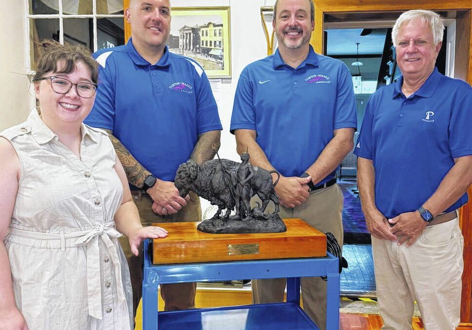 Four individuals standing around a sculpture