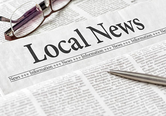 Local newspaper with glasses and pen